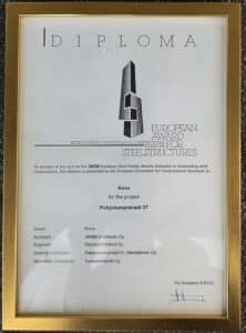 Kevalle Pohjoisesplanadi 37:n hankkeesta myönnetty, kehyksessä oleva vuoden 2026 Euroopan teräsrakenteiden palkinnon todistus, jossa mainitaan arkkitehti, insinööri, pääurakoitsija ja teräsrakenteiden urakoitsija.